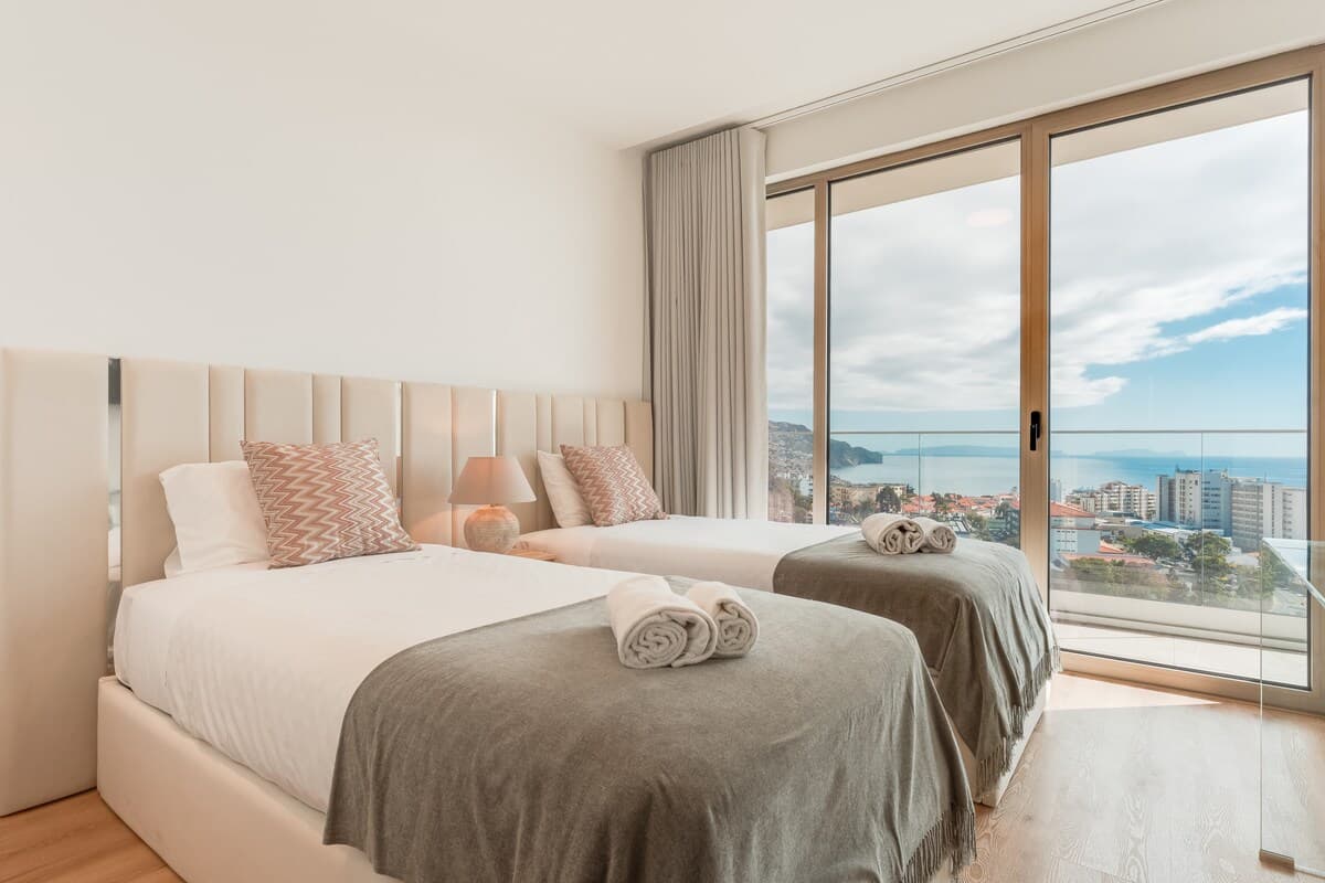 Relax in style and comfort in the bright second bedroom featuring two cozy single beds and soothing natural light — a peaceful retreat for restful nights.